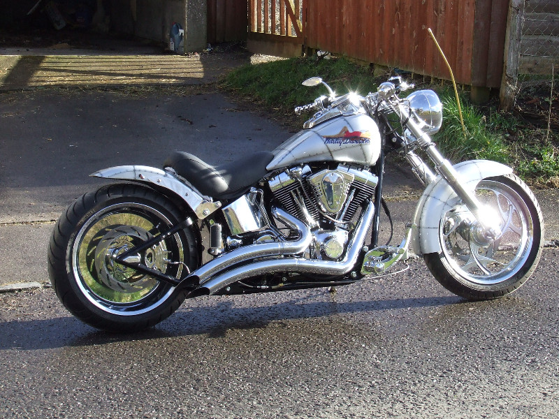 Lightning's Airplane bike. raked and detinned twin Cam Fatboy, Adjure headlamp, WIIIDE Flyer bars, Vance and Hines exhaust Ness front and 250 Rev Tech rear Chromed Billet wheels, One off seat and rear fender. Paint by our partner Reef Paintshop. Sunshine on rainy delivery day . . .pure luck!